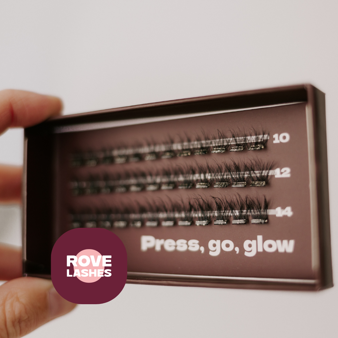 A hand holds a tray of Rove Lashes false eyelashes. The dark brown tray displays three rows of black lashes labeled 10, 12, and 14, with the slogan 'Press, go, glow' printed on the front.