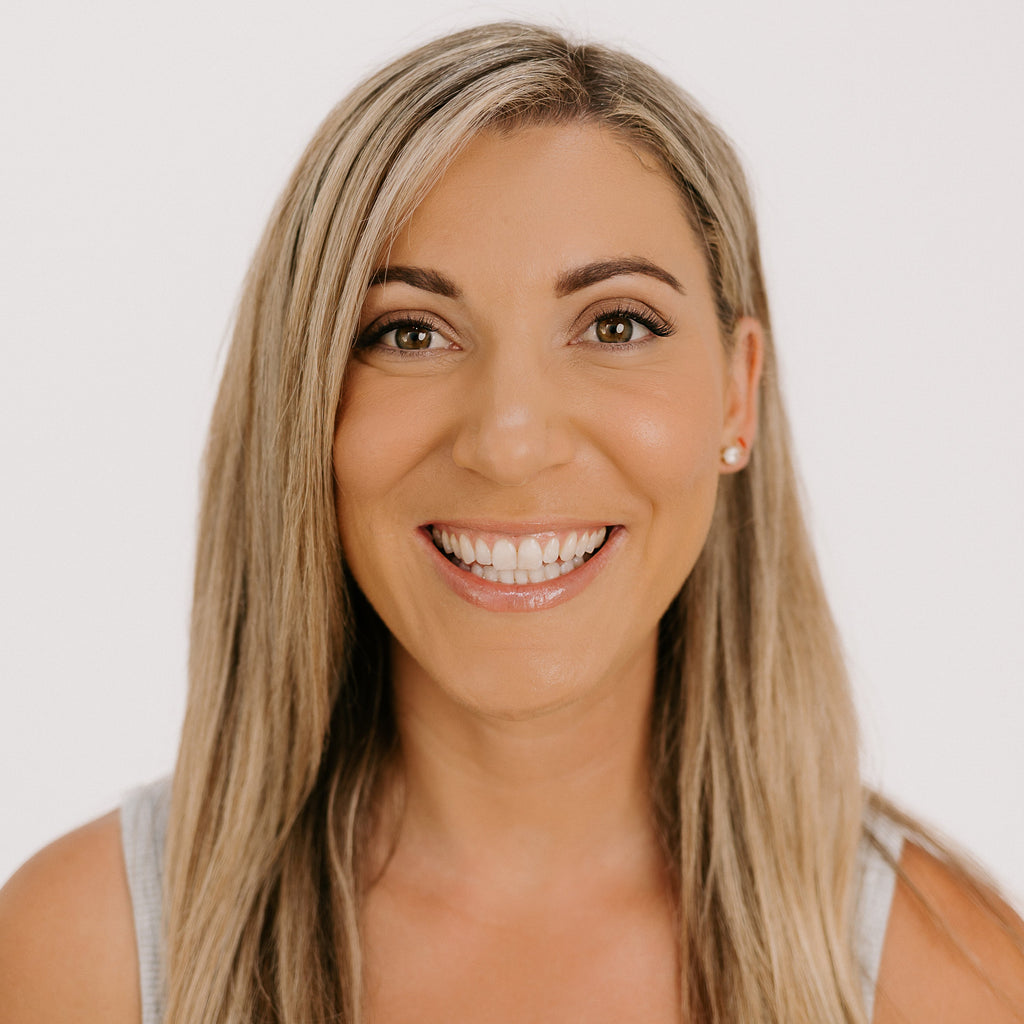 Woman with blonde hair smiling against a white background wearing rove lashes