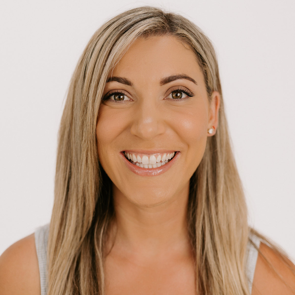 Woman with blonde hair smiling against a white background wearing rove lashes